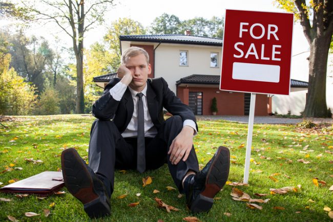 Worried real estate agent and house for sale