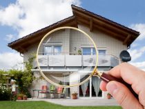 Hand With Magnifying Glass Over House