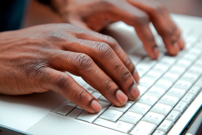 Close up of African hands on a keyboard