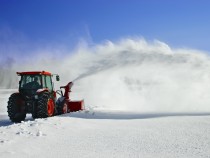 Snow is being removed by a snow blower.